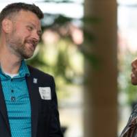 Two staff members smile while chatting at the celebration
